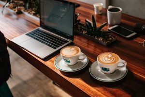 Tasses de café sur un bureau en bois à côté d'un ordinateur