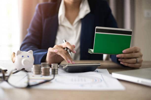 Femme qui calcule des frais avec une calculatrice et un chéquier dans la main