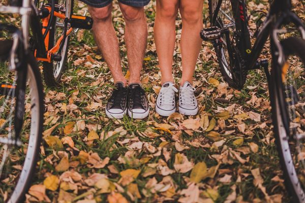 homme et femme près de vélos portant des converses sur un sol avec feuilles mortes