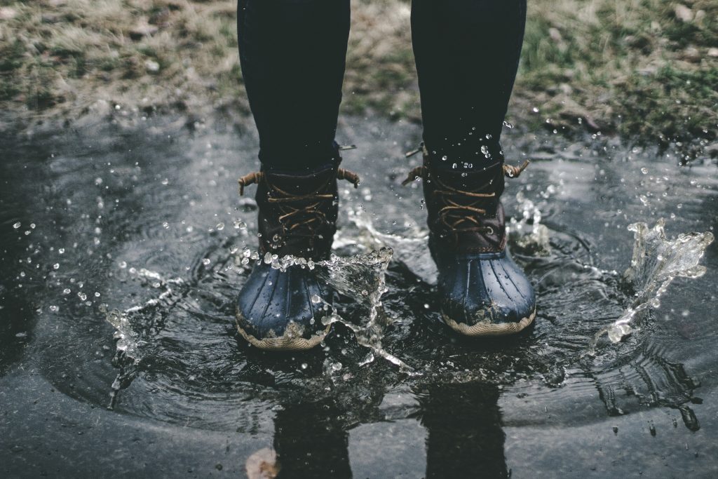 personne portant des boots noires dans une flaque d'eau