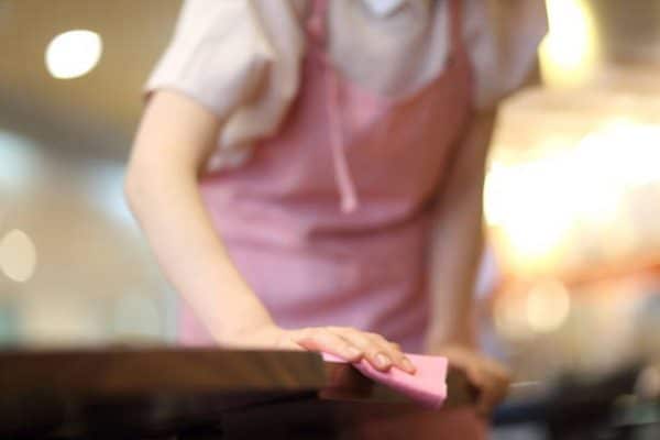 Gros plan sur une femme de ménage qui nettoie une table avec une microfibre