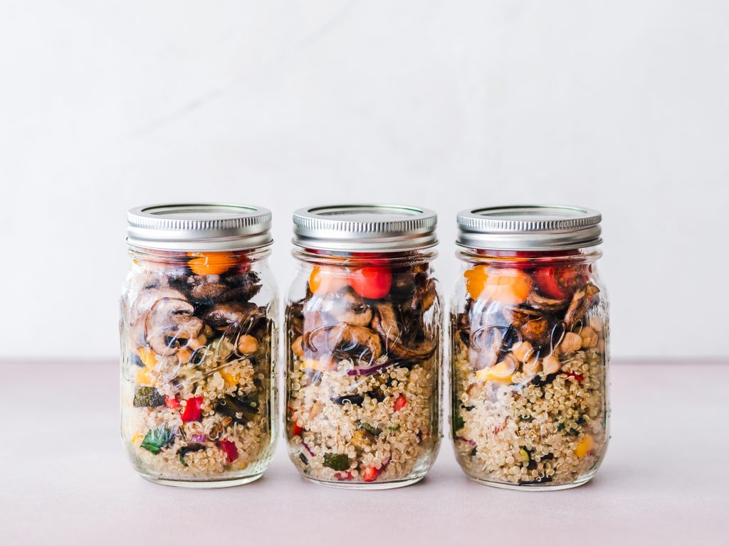 3 salades préparées dans des pots en verre transparent avec quinoa, tomates, champignons