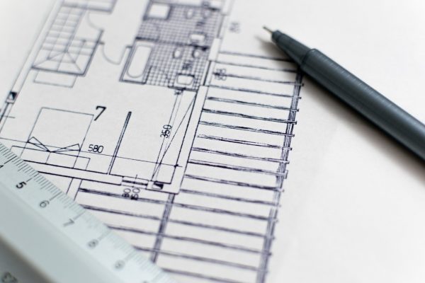 Zoom sur un plan d'architecte sur lequel sont posés un crayon et une règle