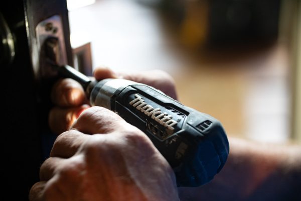 vue sur les mains d'une personne tenant une perceuse makita